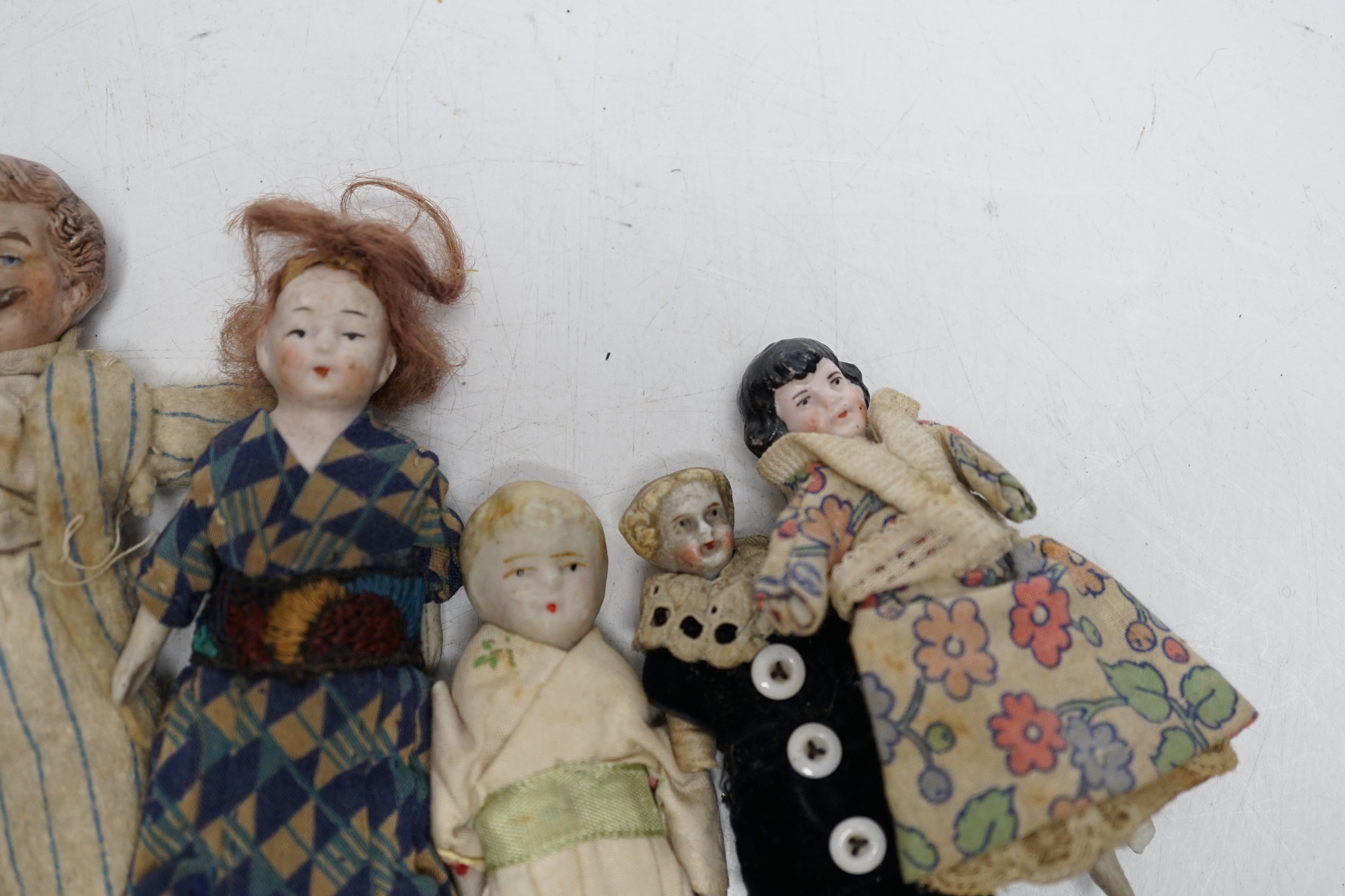 Six doll's house dolls, two c.1860 and a male figure with moustache, two other bisque later figures and one small doll, damaged